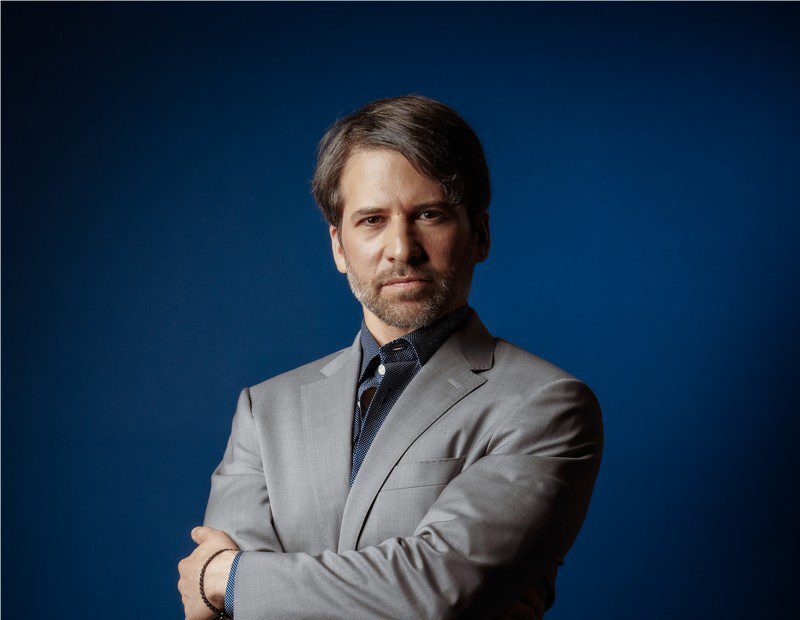 Aron Boxer, M.Ed., S.P.E., in a gray suit against a blue backdrop